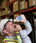 PhysiciansCare Eye Wash Solution, 16-oz white bottle with blue label, used to flush an eye in a warehouse.