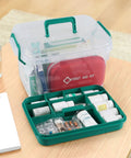 1 Pack Plastic Medicine Storage Kit All In One With Detachable Green Tray And Eight Grid Compartments Clear First Aid Storage Box With Sturdy Handles Portable Household Organizer For Meds And Small Supplies, open view showing organized supplies with green tray on a wooden table.
