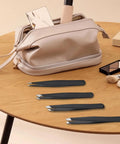 4 Piece Stainless Steel Tweezers Set Black Finish For Precision Grooming And Brow Game on table with makeup bag and tools