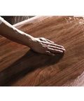Hand running over the smooth surface of the Straight Up Solid Wood Electric Standing Desk With Drawers.