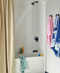 Matte black tub and shower trim kit with 6-function shower head spraying water in a bathroom; includes reliable valve trim upgrade.
