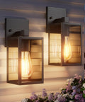 All Season Black Wall Sconces Built Tough To Beat The Elements With Heavy Duty Aluminum And Rainproof Glass E26 Socket Waterproof Exterior Lights For Porches Driveways And Garages Two Pack Set mounted on a wall with a warm glow.