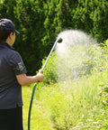 Person using a RelaxGrip 33 Inch Shower Head Watering Wand with Quick Connects and GentleRain Shower Head in a garden.