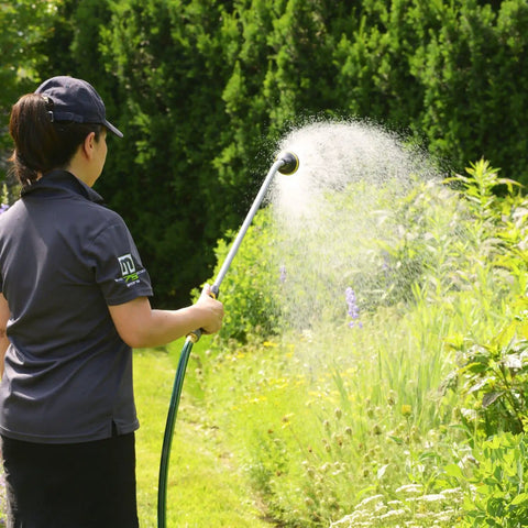 Person using a RelaxGrip 33 Inch Shower Head Watering Wand with Quick Connects and GentleRain Shower Head in a garden.