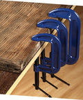 Side view of three Heavy Duty 4 Inch G Clamp Table Mounts securing wood on a workbench for woodworking and metalworking projects.