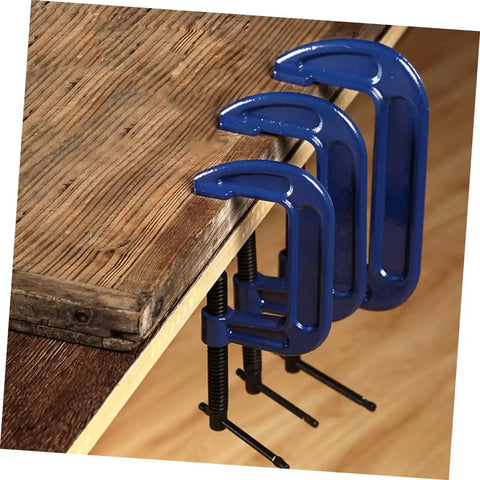 Side view of three Heavy Duty 4 Inch G Clamp Table Mounts securing wood on a workbench for woodworking and metalworking projects.