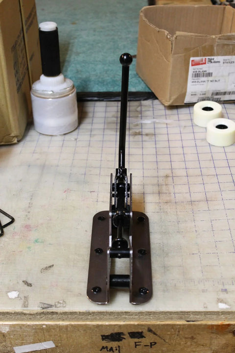 Bearing press and puller, black metal, on workbench with cardboard boxes in background.