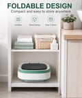 Compact Portable Foldable Washer With Amped Up Motor And Three Wash Cycles on shelf with towels and plants.