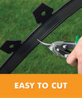 Cutting flexible recycled plastic of Tall Wall No Dig Landscape Edging Kit for DIY Gardens, includes three 30 ft coils and 24 spikes.