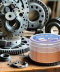 Copper Grease High Temperature Assembly Lubricant Pro Grade Heavy Duty tub in front of metal gears for industrial use