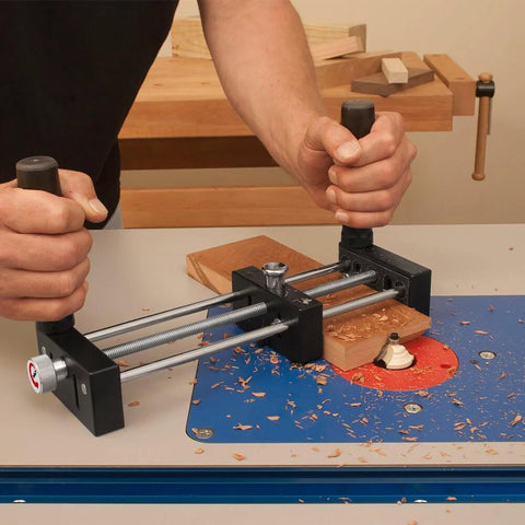 Small Stock Holder For Router Tables That Secures Tiny Wood Pieces And Lets You Feed Wood Safely Keeping Fingers Clear And Delivers Precise Freehand Cuts On Any Router Table holding wooden piece on a router table with blue surface.