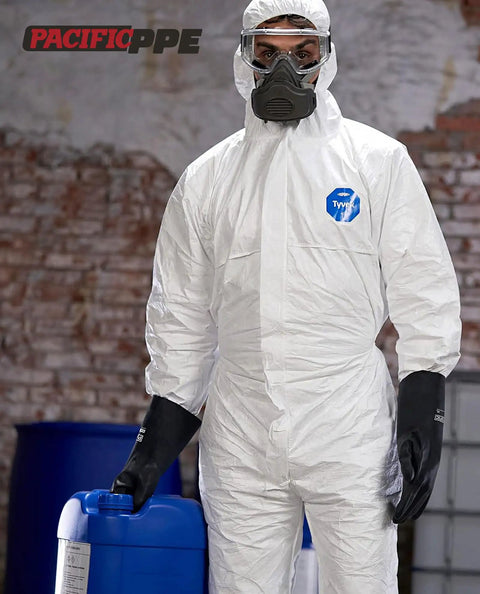 Person wearing white protective suit and Chemical Resistant Work Gloves Built To Take A Beating Heavy Duty Industrial Latex Rubber Gloves That Stand Up To Acids Alkalis Oils And Solvents Ergonomic 12.6 Inch Large Reusable 2 Pairs For Lab Shop Or Construction, holding a blue chemical container.