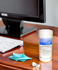 Audio-Wipes cleaning towelettes large white canister; blue cleaning cloth and hearing aid battery keychain on desk.