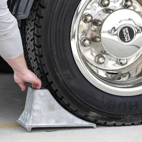 Person using Beefy Aluminum Wheel Chock With Rugged Teeth For Extra Grip And Stability Steep Slope Design 55000 Lb Capacity Heavy Duty Parking Tool For Trucks And Rigs 6.25 X 12.25 X 7 Inch Silver on truck.