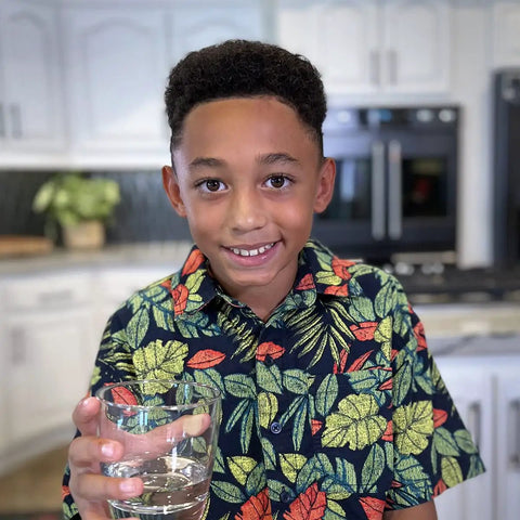 Child holding a glass of water in a kitchen, demonstrating Undersink Replacement Filter Cartridge For U9000 Systems, 1000 Gallon Capacity.