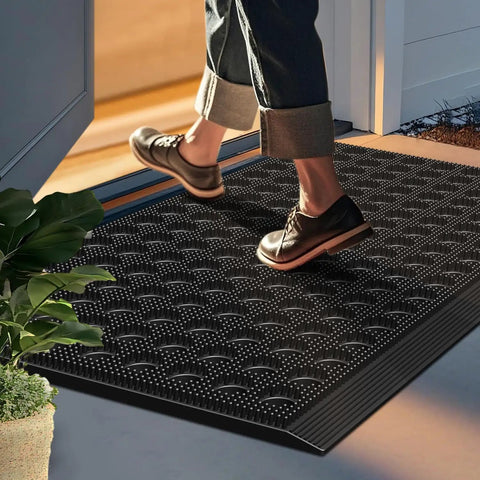 Person stepping onto Heavy Duty Outdoor Doormat With All Weather Waterproof Construction Non Slip Drainage Entry Mat For Garage Home Pool Or Commercial Use Dirt Trapper Welcome Rug 17 By 29.5 Inches Black at a home entrance