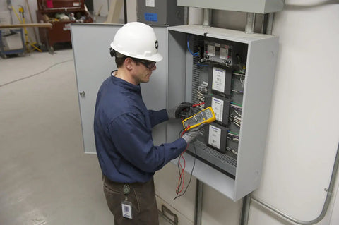 Technician using True-RMS Digital Multimeter Pro Grade Shop-Ready with 6000 Count Scale on electrical panel.