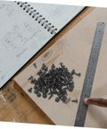 Miniature Metal Screws Set Of 100 Self Tapping Mounting Fasteners For Furniture Repair And DIY Projects laid on wood with notebook and ruler