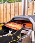 Heavy Duty Heat Resistant Grill Gloves For Outdoor Cooking With Dope Wrist Protection To Stop Burns Ideal For Grilling Barbecues Fireplaces Pizza Ovens And Charcoal Grills holding a pizza tray near a pizza oven