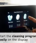 Finger selecting cleaning function on VeroCafe 800 Series espresso machine display featuring Calc'nClean, Cleaning, Descaling.