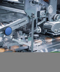 Industrial packaging machine wrapping products with plastic and sealing, showcasing automation and precision engineering equipment.