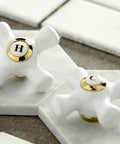 Close-up of white hot and cold faucet handles on marble tiles