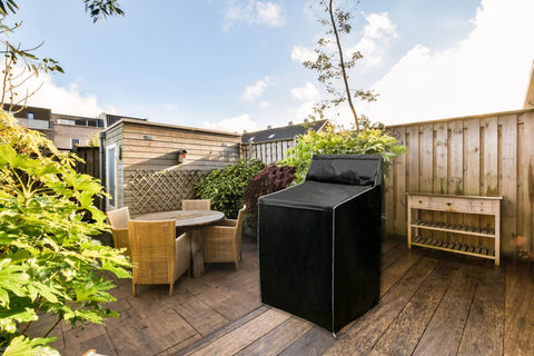 Front view of a black fabric washer and dryer cover on an outdoor wooden deck
