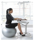 Adjustable Mobile Overbed Table Featuring Smooth Rollin Casters And Beastly Stable Base used as a laptop desk beside a ball chair.