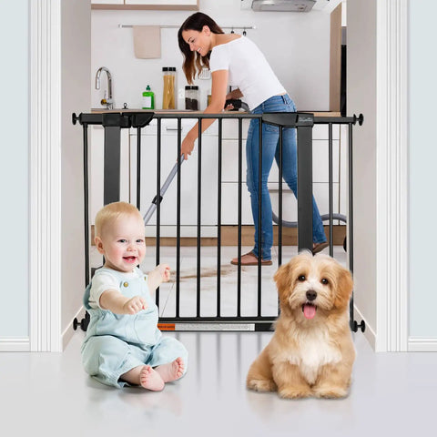 Extra Wide Walk Through Pet Gate With Auto Close Durable Metal Baby And Pet Gate For Stairs And Doorways Forty Point Five Inches Full Width Includes 2 Extension Kits Black installed in a kitchen doorway with baby and dog sitting in front