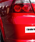 Rear bumper sticker on a red car; white decal reads i brake for with a small photo.