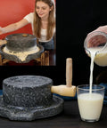 Woman grinding flour with Hand Crank Stone Grain Mill With Granite Grinding Stone And Sturdy Wood Base, glass of milk nearby.