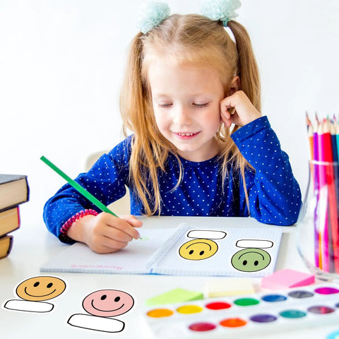 Child writing at desk with Smiley Name Tags Pack 120 Pcs Boho Pastel Smile Face Nameplates For Classroom And Office Labeling.