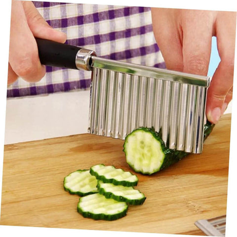 Stainless steel wavy chopper with ergonomic black handle slicing cucumber on a wooden cutting board