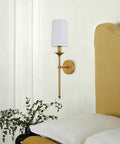 Top Shelf Vintage Antique Brass Wall Sconce Set Of 2 Hardwired Farmhouse Lights With Smooth White Glass Shades next to a yellow headboard.