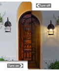 2 Pack Outdoor Wall Sconce Lanterns lit and unlit on porch beside wooden door, black exterior with clear glass shade