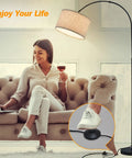 Slick Arc LED Floor Lamp With Marble Base For Living Room, rotatable hanging light over woman on sofa, beige linen shade