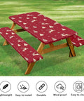 Christmas Reindeer Fitted Picnic Table and Bench Cover Set with reindeer design on a wooden table in a grassy backyard.