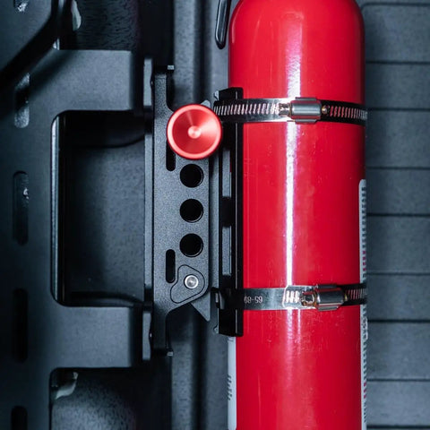 Slick Under Seat Fire Extinguisher Bracket For Ineos Grenadier Truck With One Hand Quick Release Aluminum Mount Kit And Heavy Duty Secure Ratchet Straps displaying fire extinguisher securely mounted.