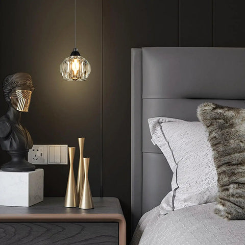 Three Light Matte Black Pendant Lighting With Transparent Glass Shades above a modern bedroom nightstand and decor