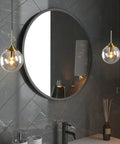 Mid Century Modern Brushed Gold Pendant Light with Plug In Cord, Smoke Gray Glass Globe hanging beside a round mirror in a bathroom