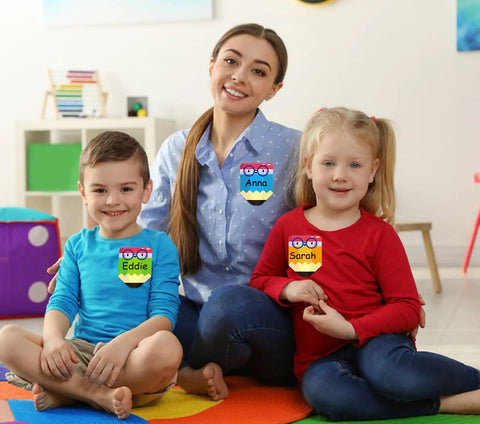 Teacher and students wearing Colorful 36 Pack Pencil Desk Name Plates with Waterproof PET Film for classroom organization.