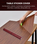 Realistic Brown Wood Grain Peel And Stick Wallpaper Self Adhesive Vinyl Removable Film being applied on a wooden table surface.