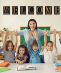 Fresh Industrial Chic Bulletin Board Poster Set Leveling Up Classroom Vibe With Seven Welcome Cutouts And Six Motivational Prints Perfect Teacher Decor Game Changer Glue Dots Included, students and teacher in classroom smiling with 'WELCOME' display.