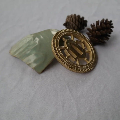 Copper Tsuba Hand Guard For Katana Wakizashi Or Tanto with yellow finish displayed on fabric with decorative elements