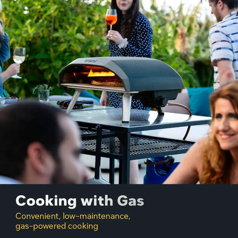 Koda 16 Natural Gas Pizza Oven for Outdoor Cooking 16 inch gas powered pizza oven with regulator and hose in use on patio table.