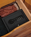 Slick Hidden Drawer Safe With Electronic Lock And Backup Key For Desk Or Nightstand Built Tough From Solid Steel Construction inside a drawer next to gloves.