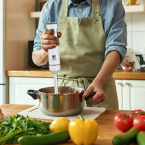 Total Game Changer Cordless Hand Blender With Integrated Whisk blending ingredients in a pot surrounded by fresh vegetables.