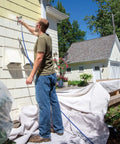Man using the Zero Sweat Heavy Duty Airless Paint Sprayer With Adjustable Pressure Control to paint a house exterior.