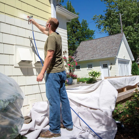 Man using the Zero Sweat Heavy Duty Airless Paint Sprayer With Adjustable Pressure Control to paint a house exterior.
