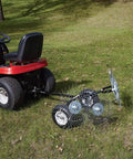 Acreage Lawn Rake With Four Tine Steel Tow Behind Dethatcher attached to a red lawn tractor on a grassy lawn, 48 inch wide.